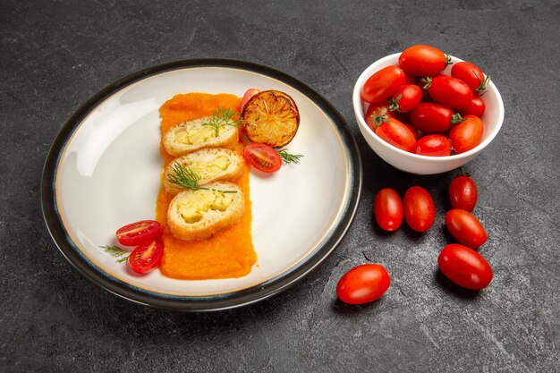 Widok z przodu pyszne placki ziemniaczane z dynią i świeżymi pomidorami na ciemnoszarym tle piekarnik piec kolorowy danie obiadowy kawałek