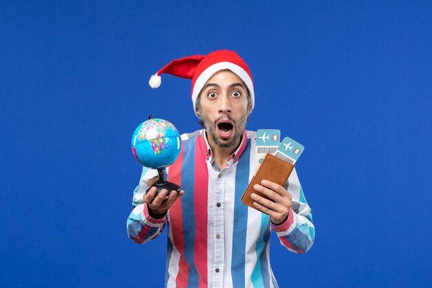 Widok z przodu regularny mężczyzna z biletami i kula ziemska na niebieskim kolorze świątecznym na biurko