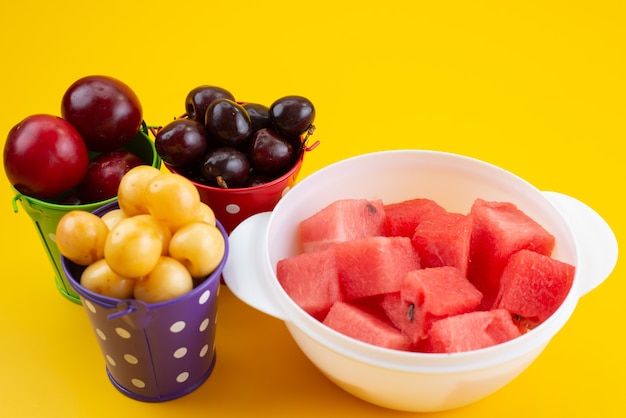 Widok z przodu różne owoce w koszykach z plasterkami arbuza na żółtej, kolorowej kompozycji owoców