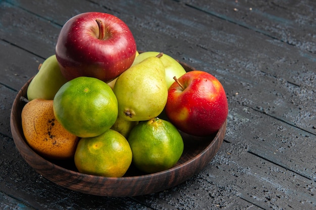 Widok z przodu różne świeże owoce jabłka gruszki i mandarynki wewnątrz talerza na ciemnoniebieskim biurku kompozycja kolorów owoców świeże dojrzałe