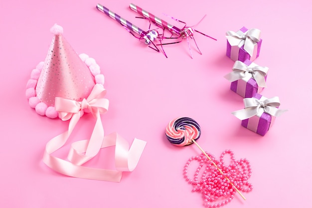 Widok z przodu różowe dekoracje urodzinowe małe fioletowe pudełka na prezenty kokardki słodki lizak na różowym tle