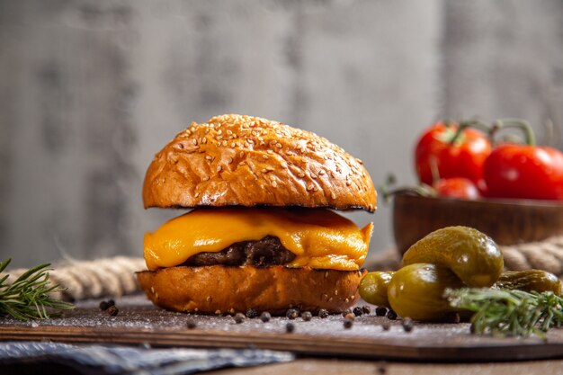 Widok z przodu serowy burger mięsny z piklami i pomidorami na drewnianym biurku