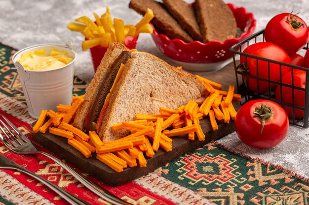 Widok z przodu smaczna kanapka tostowa z szynką serową wraz z frytkami kwaśnymi pomidorami na białym tle
