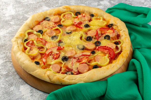 Widok z przodu smaczna serowa pizza z kiełbasami z czarnych oliwek i czerwonymi pomidorami na szarym biurku