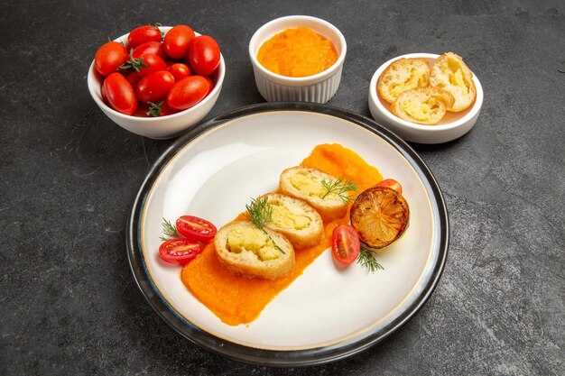 Widok z przodu smaczne placki ziemniaczane z dynią i świeżymi pomidorami na szarym tle piec obiad w piekarniku kolorowe danie dojrzałe