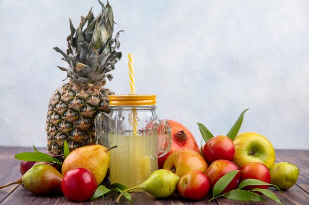 Widok z przodu soku ananasowego z owocami jako ananas brzoskwinia śliwka jabłko granat na powierzchni drewnianej i białej powierzchni