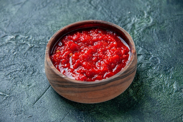 Widok z przodu sos pomidorowy wewnątrz brązowego talerza na ciemnoniebieskiej powierzchni pomidor czerwony kolor przyprawa pieprz sól
