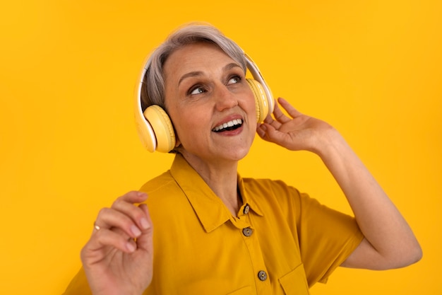 Bezpłatne zdjęcie widok z przodu starsza kobieta pozuje ze słuchawkami