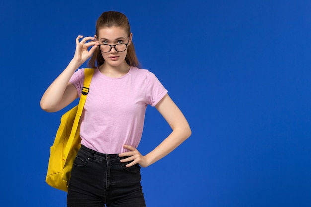 Widok z przodu studentki w różowej koszulce z żółtym plecakiem