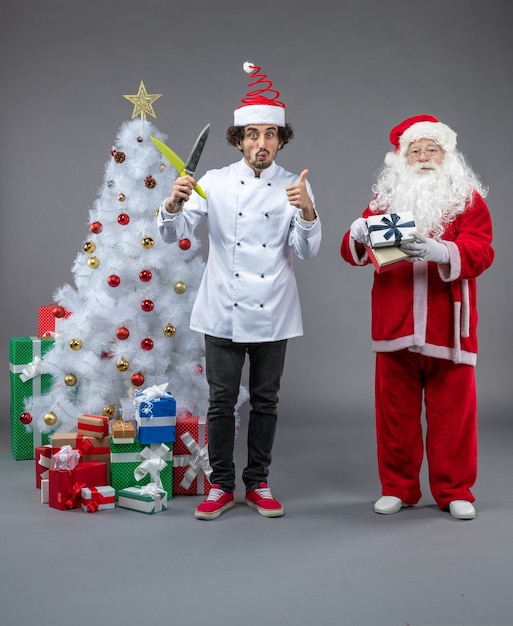 Widok z przodu Świętego Mikołaja wokół świątecznych prezentów z męskim kucharzem