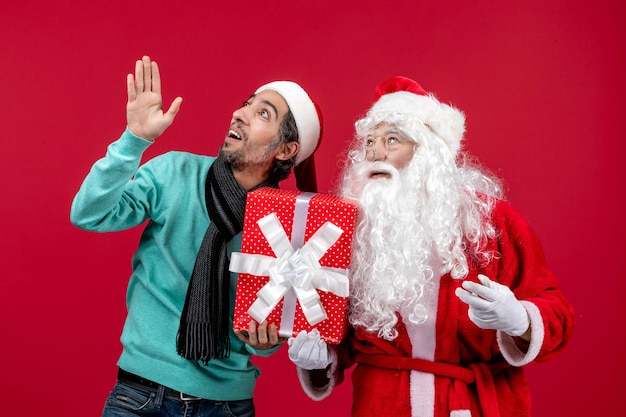 Widok z przodu święty mikołaj z mężczyzną trzymający świąteczny prezent na czerwonych prezentach emocje czerwony boże narodzenie nowy rok