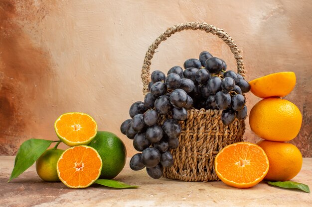 Widok z przodu świeże czarne winogrona z pomarańczą na jasnym tle łagodne zdjęcie dojrzałe owoce drzewo witaminowe