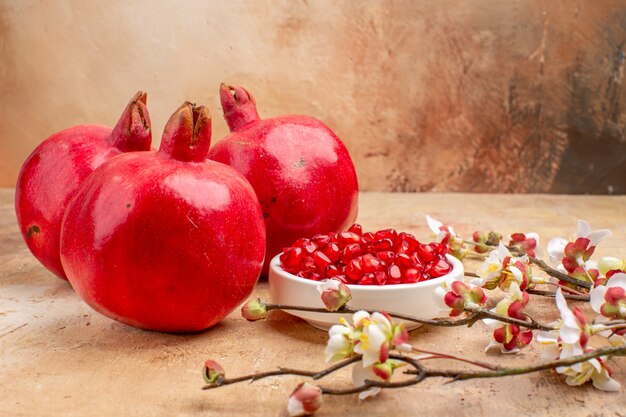 Widok z przodu świeże czerwone granaty obrane i z całymi owocami na brązowym tle kolorowe zdjęcie owoców
