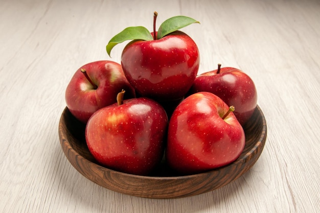 Widok z przodu świeże czerwone jabłka dojrzałe i aksamitne owoce na białym biurku kolor owoców drzewo świeża roślina czerwona