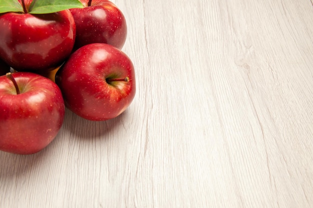 Bezpłatne zdjęcie widok z przodu świeże czerwone jabłka łagodne i dojrzałe owoce na jasnym białym biurku kolor owoców świeża roślina czerwone drzewo
