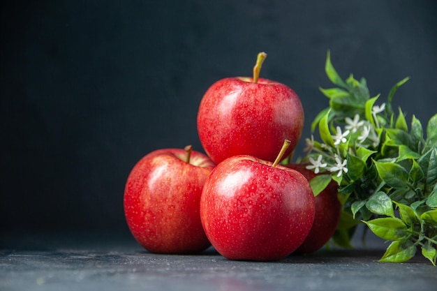 Widok z przodu świeże czerwone jabłka z zieloną rośliną na ciemnym tle łagodna gruszka jabłko jedzenie dojrzałe kolory dieta witaminowa