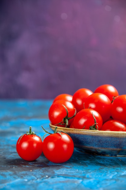 Widok z przodu świeże czerwone pomidory wewnątrz talerza na niebieskim stole