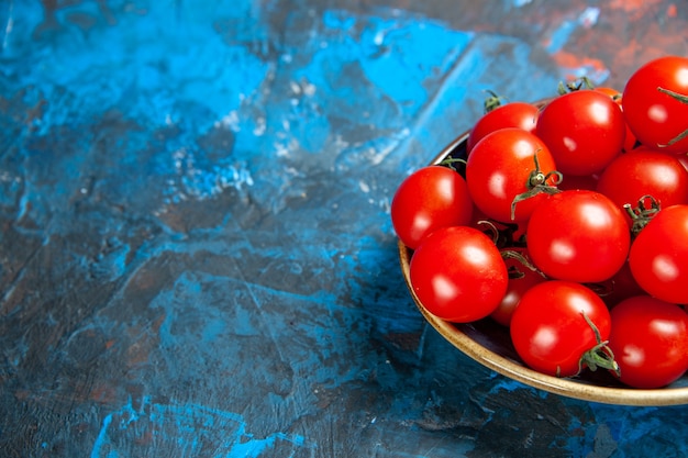 Widok z przodu świeże czerwone pomidory wewnątrz talerza na niebieskim stole