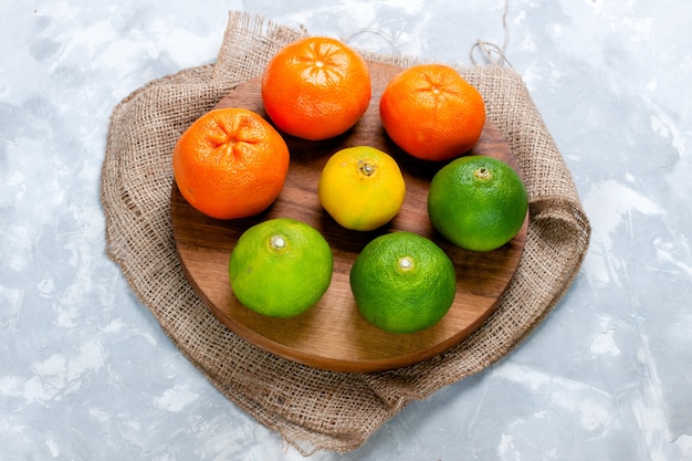 Widok z przodu świeże kwaśne mandarynki w różnych kolorach na jasnobiałym biurku kwaśne owoce cytrusowe egzotyczne tropikalne