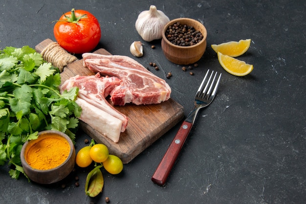 Widok z przodu świeże mięso kawałek surowego mięsa z zieleniną na ciemnym tle danie z grilla pieprz kuchnia jedzenie krowa sałatka pokarm dla zwierząt