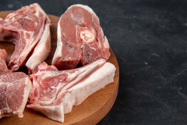 Widok z przodu świeże mięso plastry surowe mięso na okrągłym drewnianym biurku na ciemnym tle posiłek jedzenie świeżość zwierzę krowa jedzenie kuchnia