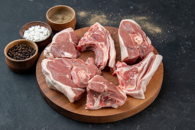 Widok z przodu świeże mięso plastry surowe mięso z przyprawami na ciemnym tle posiłek jedzenie świeżość krowa jedzenie kuchnia zwierzę