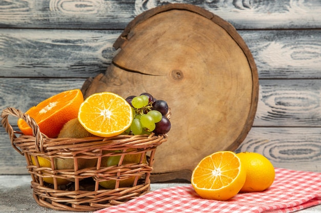Bezpłatne zdjęcie widok z przodu świeże owoce winogrona i pokrojone pomarańcze w koszu na białym tle owoce dojrzałe łagodne witaminy świeże