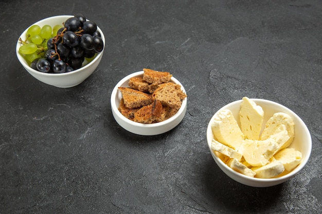 Widok z przodu świeże winogrona z białym serem i pokrojonym ciemnym chlebem na ciemnym tle posiłek jedzenie danie mleko owoce