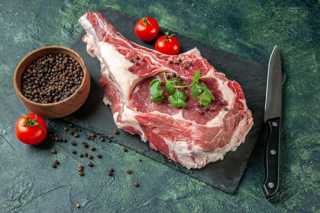 Widok z przodu świeżego kawałka mięsa z pomidorami i pieprzem na ciemnoniebieskiej kuchni zwierzę krowa kurczak jedzenie kolor mięso rzeźnika