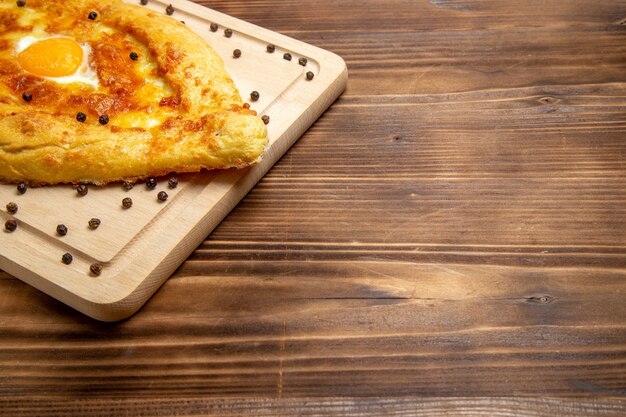 Widok z przodu świeży chleb z gotowanym jajkiem na rustykalnej powierzchni ciasto jedzenie śniadanie jajko bułka posiłek