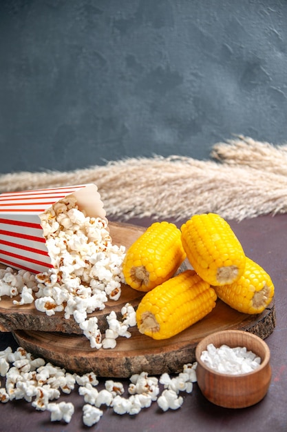Bezpłatne zdjęcie widok z przodu świeży popcorn z żółtymi pokrojonymi odciskami na ciemnej powierzchni przekąska popcorn spożywczy kukurydza