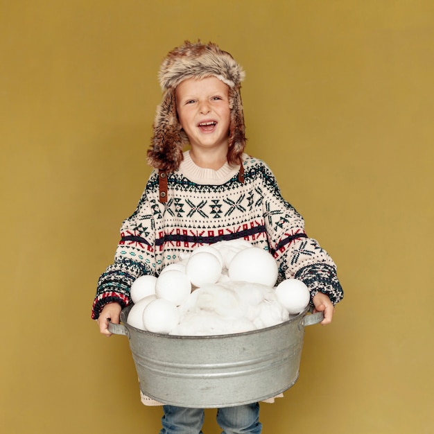 Bezpłatne zdjęcie widok z przodu szczęśliwy dzieciak z kapeluszem i śnieżkami