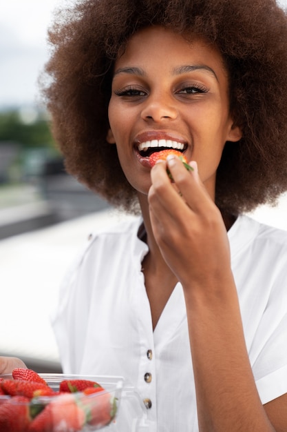 Widok z przodu uśmiechnięta kobieta jedząca truskawki