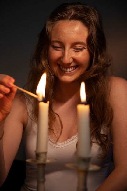 Bezpłatne zdjęcie widok z przodu uśmiechnięta kobieta zapalająca świecę