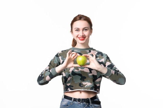 Widok z przodu uśmiechnięta młoda kobieta trzymająca zielone jabłko białe tło posiłek ludzki sok owocowy strzał dieta danie jedzenie drzewo pistolet kolory