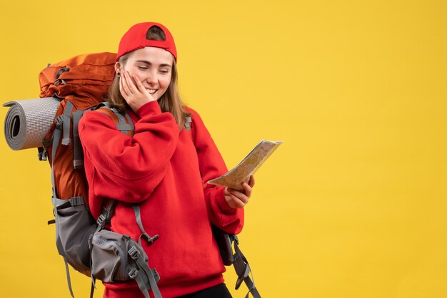 Widok z przodu uśmiechnięta turystka z czerwonym plecakiem patrząc na mapę