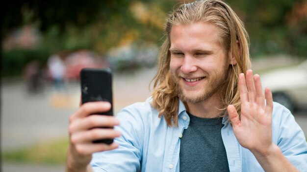 Widok z przodu uśmiechniętego człowieka, biorąc selfie na zewnątrz