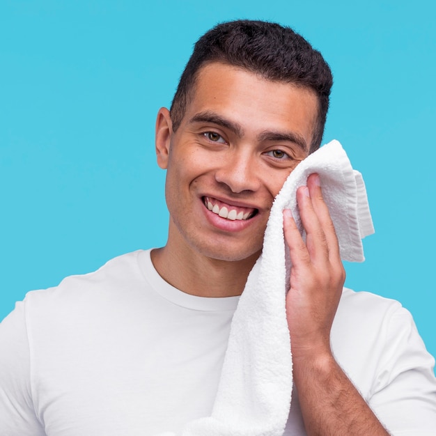 Bezpłatne zdjęcie widok z przodu uśmiechniętego mężczyzny za pomocą ręcznika na twarzy