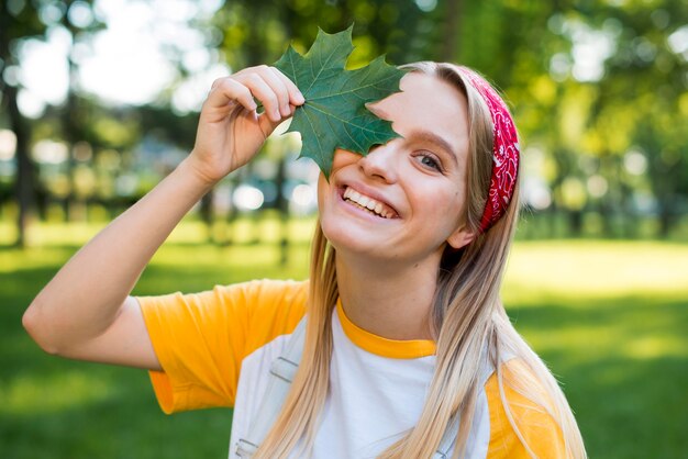 Widok z przodu uśmiechniętej kobiety stwarzających z liściem