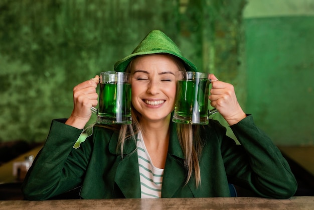 Bezpłatne zdjęcie widok z przodu uśmiechniętej kobiety w kapeluszu z okazji św. patrick's day w barze