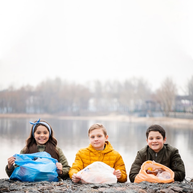 Bezpłatne zdjęcie widok z przodu uśmiechniętych dzieci z plastikowymi torbami