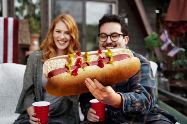 Widok z przodu uśmiechniętych ludzi z gigantycznym hot dogiem