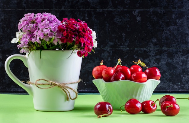 Bezpłatne zdjęcie widok z przodu wiśnia w wazonie z bukietem kolorowych kwiatów w filiżance