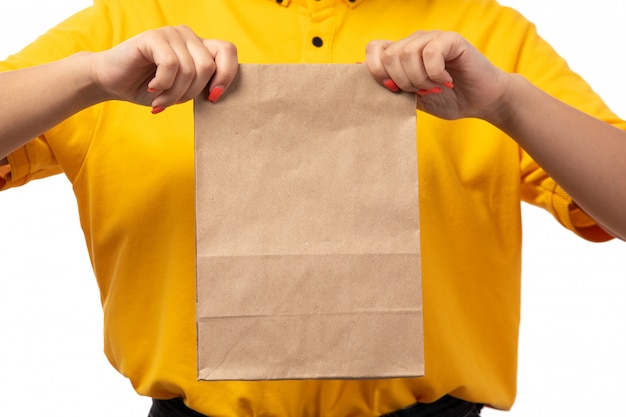 Widok z przodu żeński kurier w żółtej koszuli trzyma pakiet żywności na białym tle