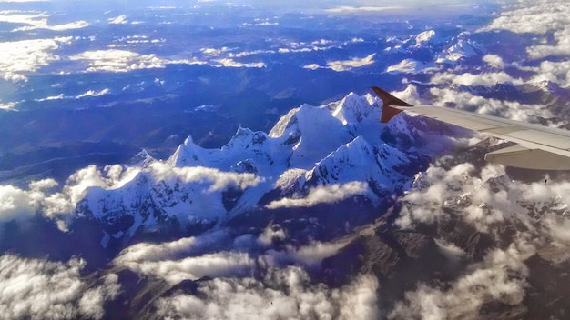 Widok z samolotu na skaliste góry pokryte śniegiem w słońcu w ciągu dnia