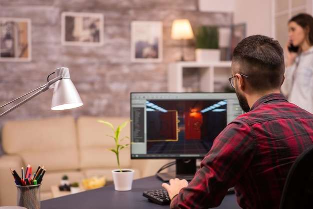 Bezpłatne zdjęcie widok z tyłu kaukaski mężczyzna grając w gry wideo na komputerze domowym. dziewczyna w tle