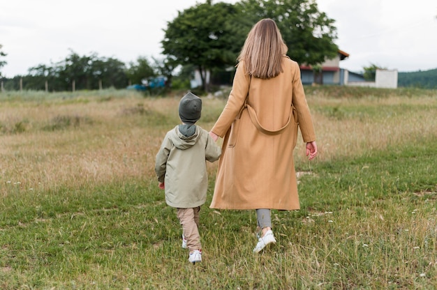 Bezpłatne zdjęcie widok z tyłu kobieta trzymająca syna za rękę