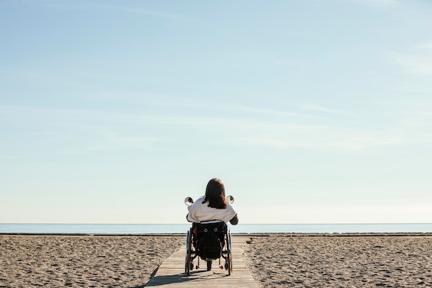 Widok z tyłu kobiety na wózku inwalidzkim na plaży
