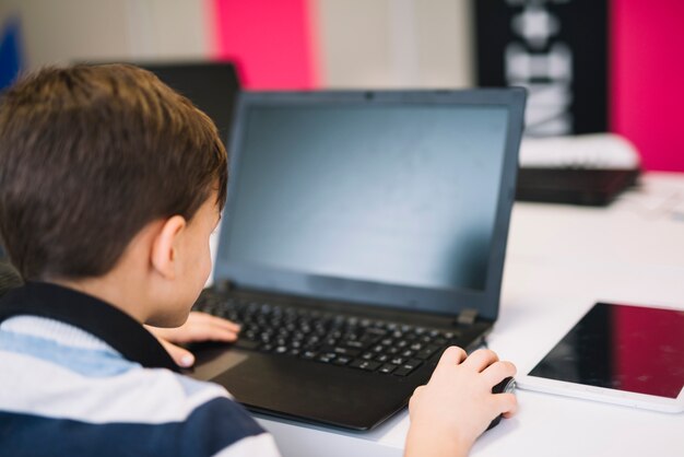 Widok z tyłu małego chłopca za pomocą laptopa i myszy