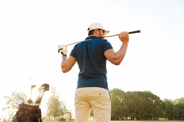 Widok z tyłu męskiego golfisty na polu golfowym z workiem klubowym